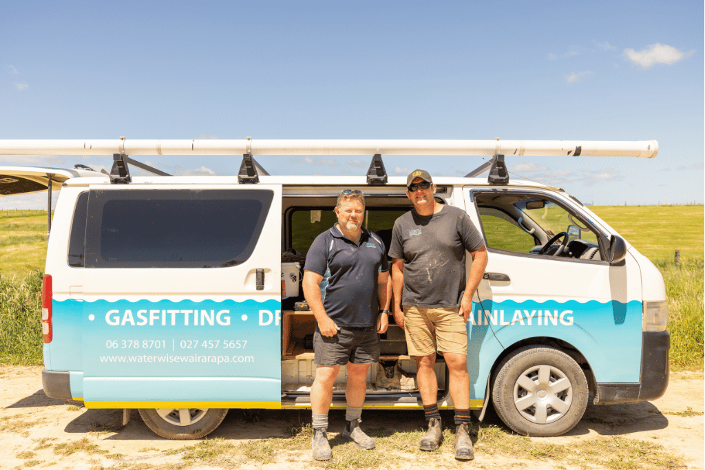 Two EarnLearn industry partners standing in front of a plumbing and drainlaying van on a rural worksite.