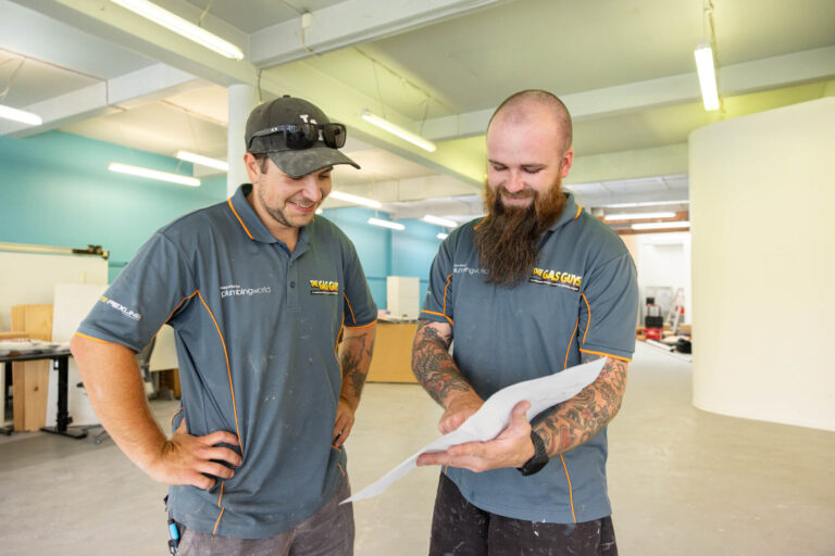 Two tradespeople in a workshop reviewing plans together.