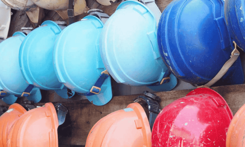 A collection of colourful hard hats hanging on a wall.