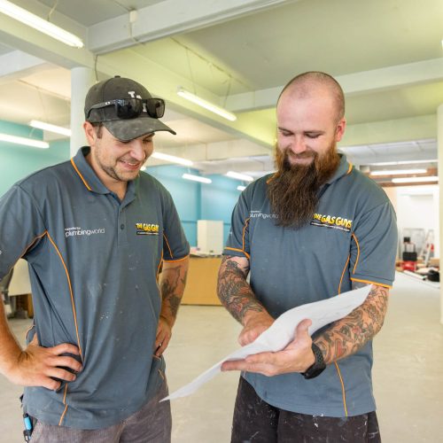 Two tradespeople in a workshop reviewing plans together.