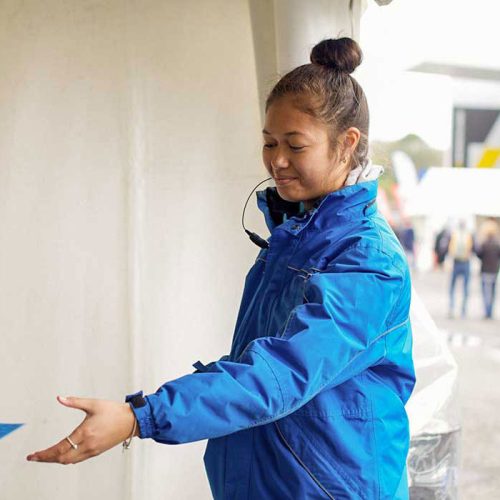 Security officer in a blue uniform directing people with a welcoming gesture.