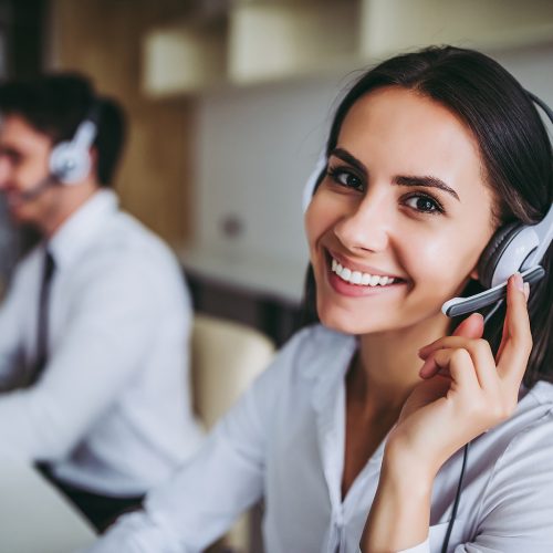 Smiling contact centre worker wearing a headset while assisting a customer.