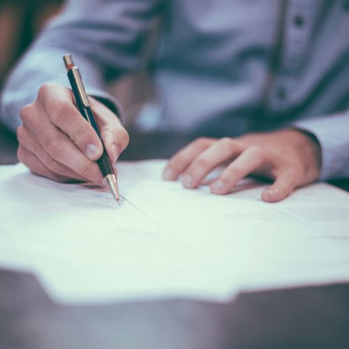 Person writing on documents at a desk, representing teaching, learning, and professional development.